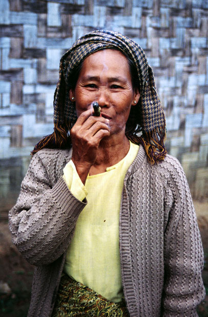 Local woman (from hill tribe) is smoking traditional burma cigar called cheroot. Area around Kalaw village. Myanmar (Burma).