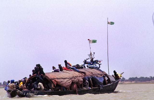 Life at Niger river. Large pinnase boat is carrying passangers and goods on the river. Mali.